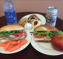 a pair of sandwiches with some pastries and bottled water in the background